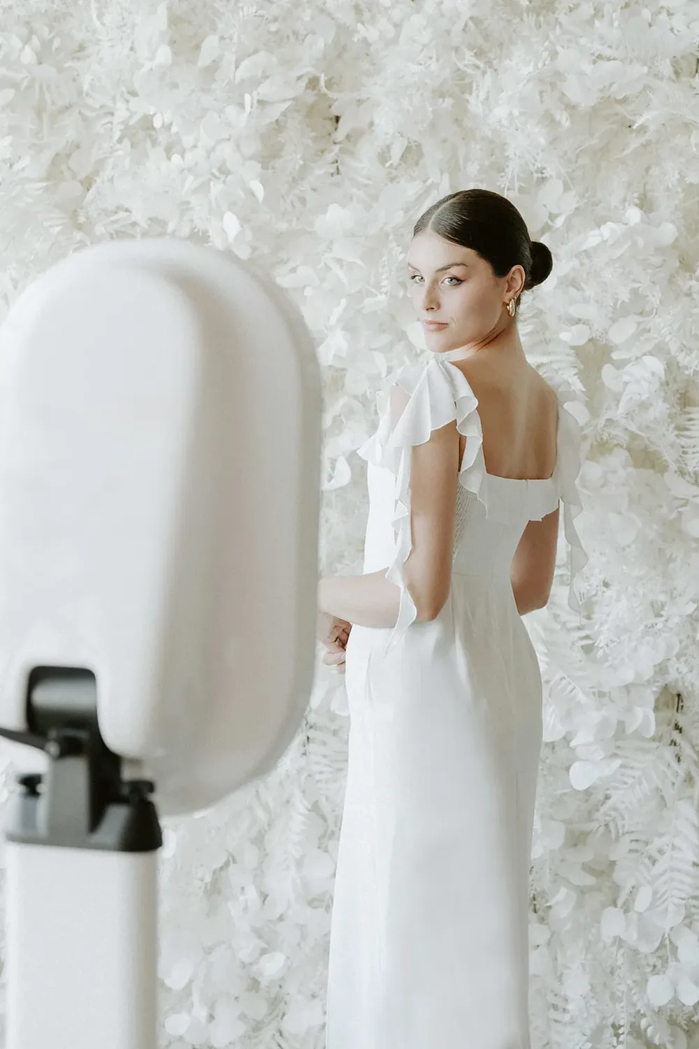 White flower wall installation with an open-air photo booth in front of it