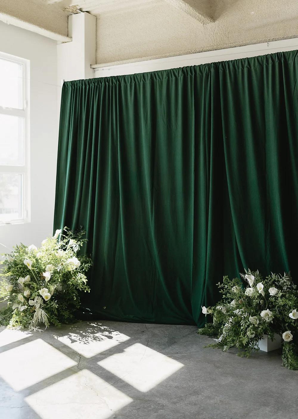 Draped fabric backdrop styled with a floor floral arrangement