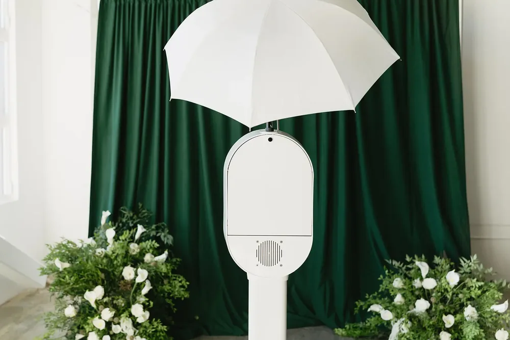 Open-air photo booth set in front of a draped backdrop with floral styling