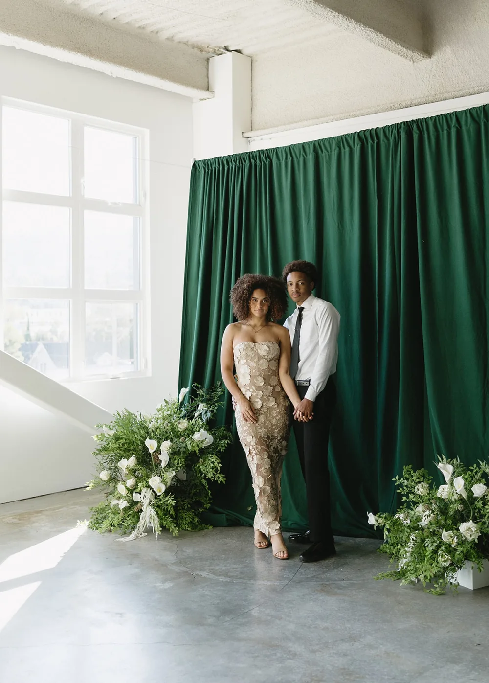 A custom drapery backdrop installation styled with white floral arrangements