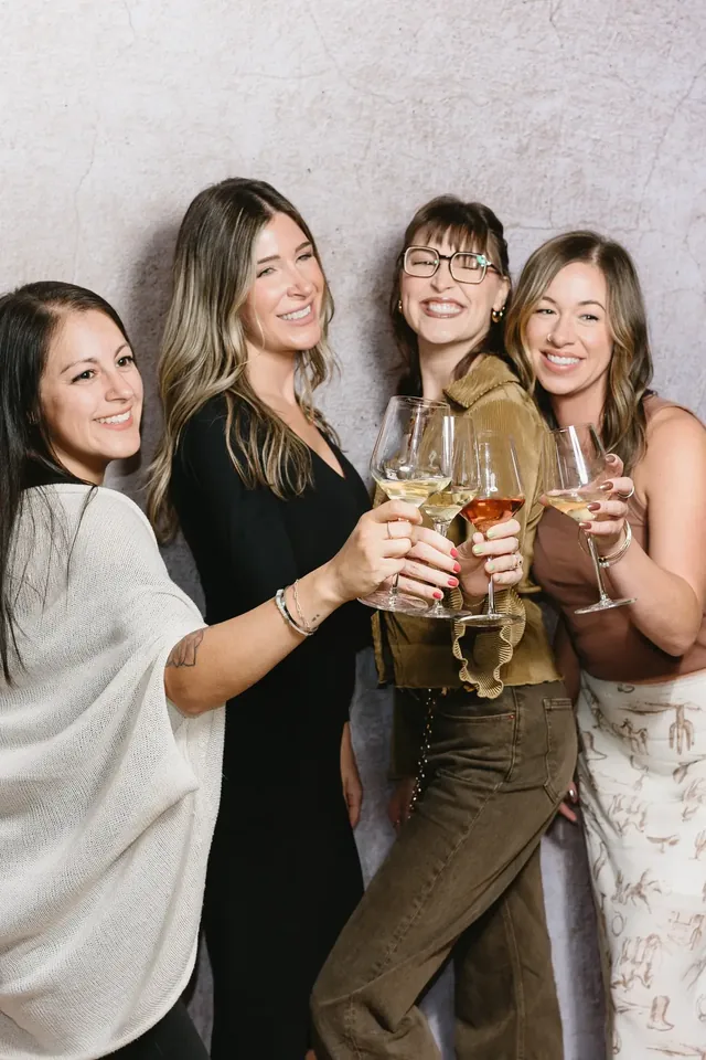 Group of guests toasting with glasses in front of a light wall
