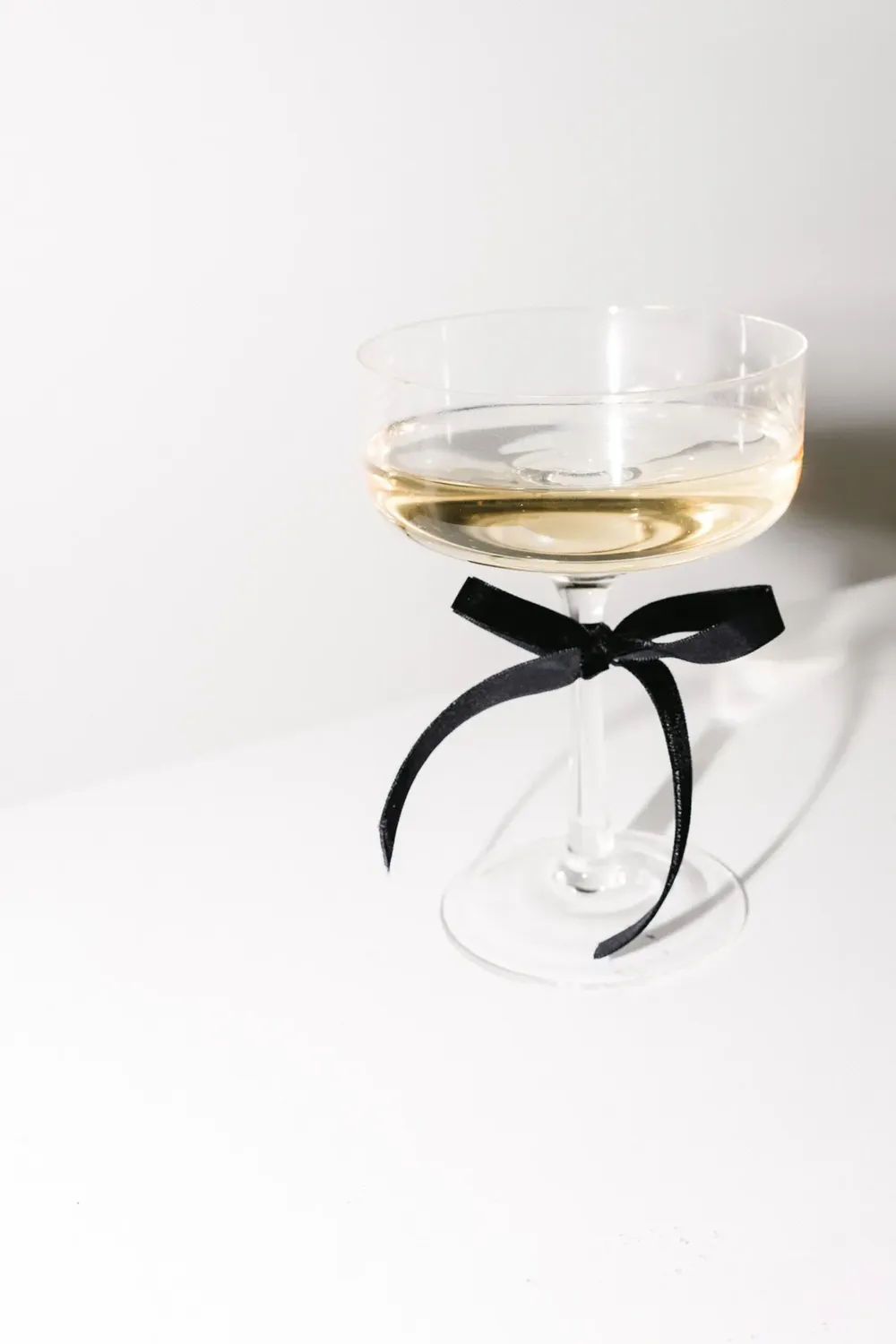 Coupe glass tied with a black ribbon on a white table.