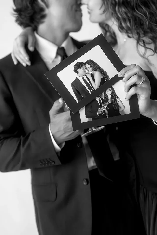 Hands holding two printed black and white photo keepsakes.