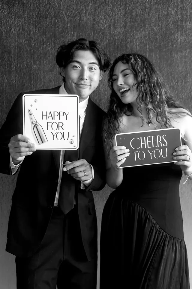 Two guests holding lettered signs in front of a dark backdrop