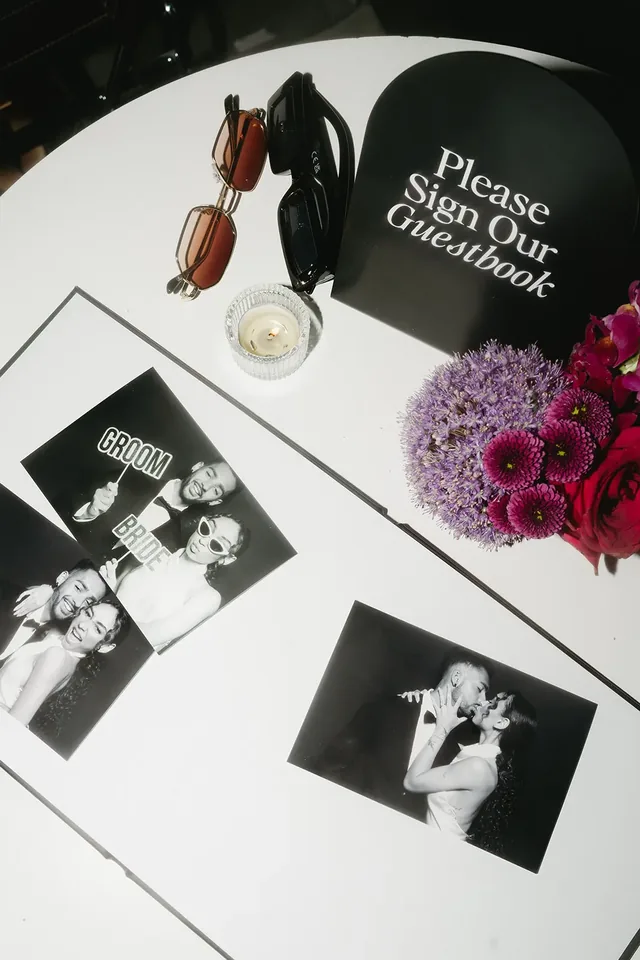 Guest book open beside printed photos on a styled table.