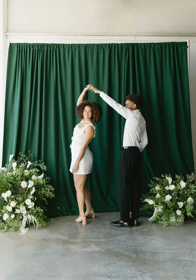 Couple dancing together in front of a draped backdrop