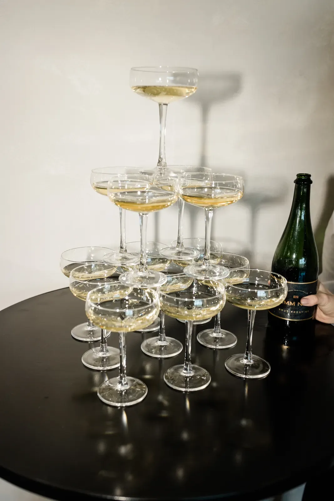 Champagne tower of coupe glasses beside a bottle