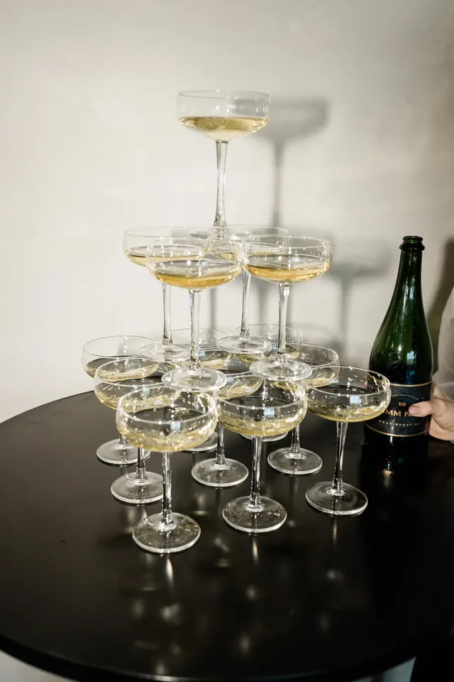 Champagne tower of coupe glasses beside a bottle