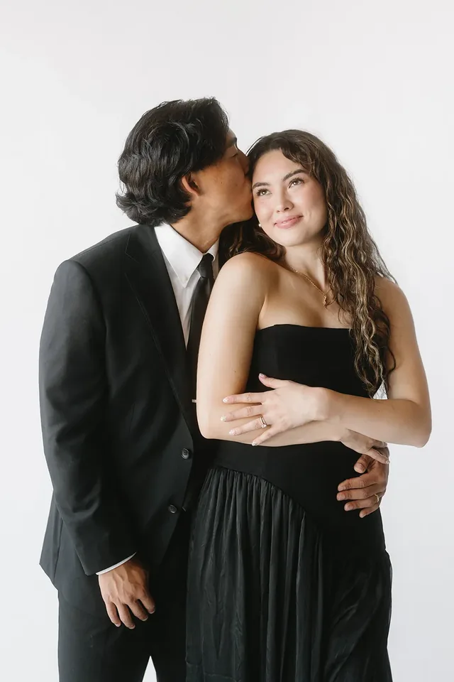 Couple in black formalwear against a bright studio backdrop