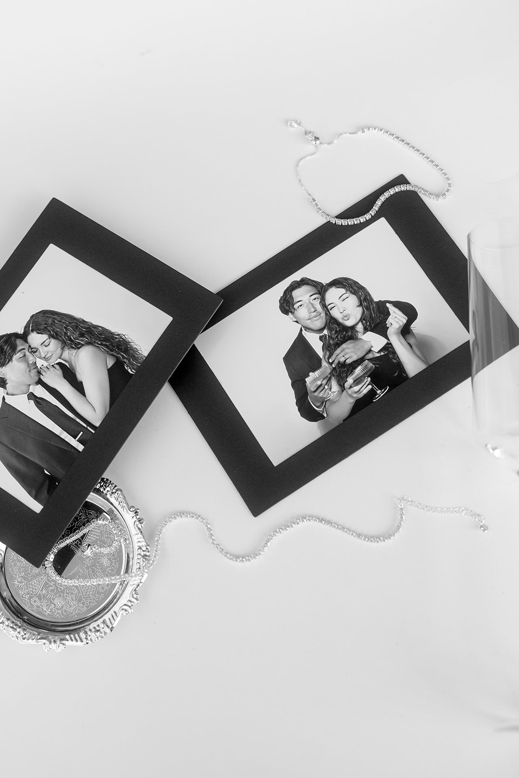 Two matted photo prints laid on a white surface beside rhinestone jewelry.