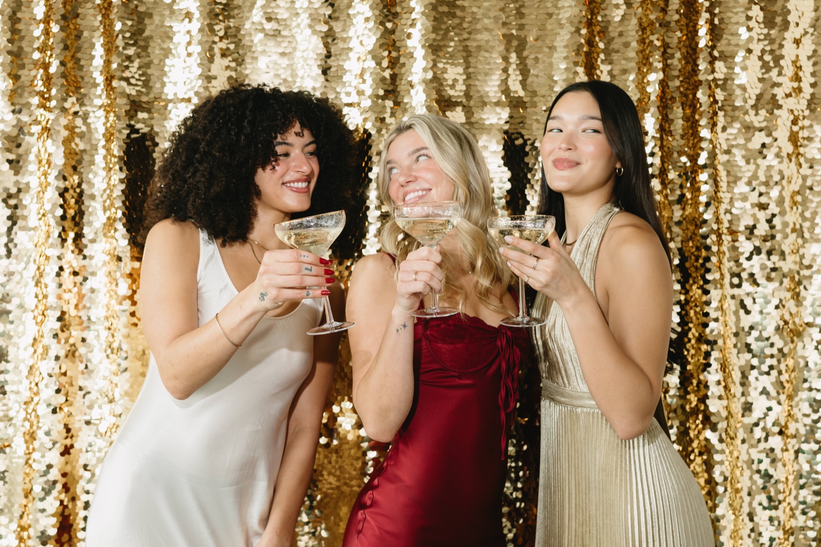 Three guests raising their glasses together in front of a shimmering backdrop